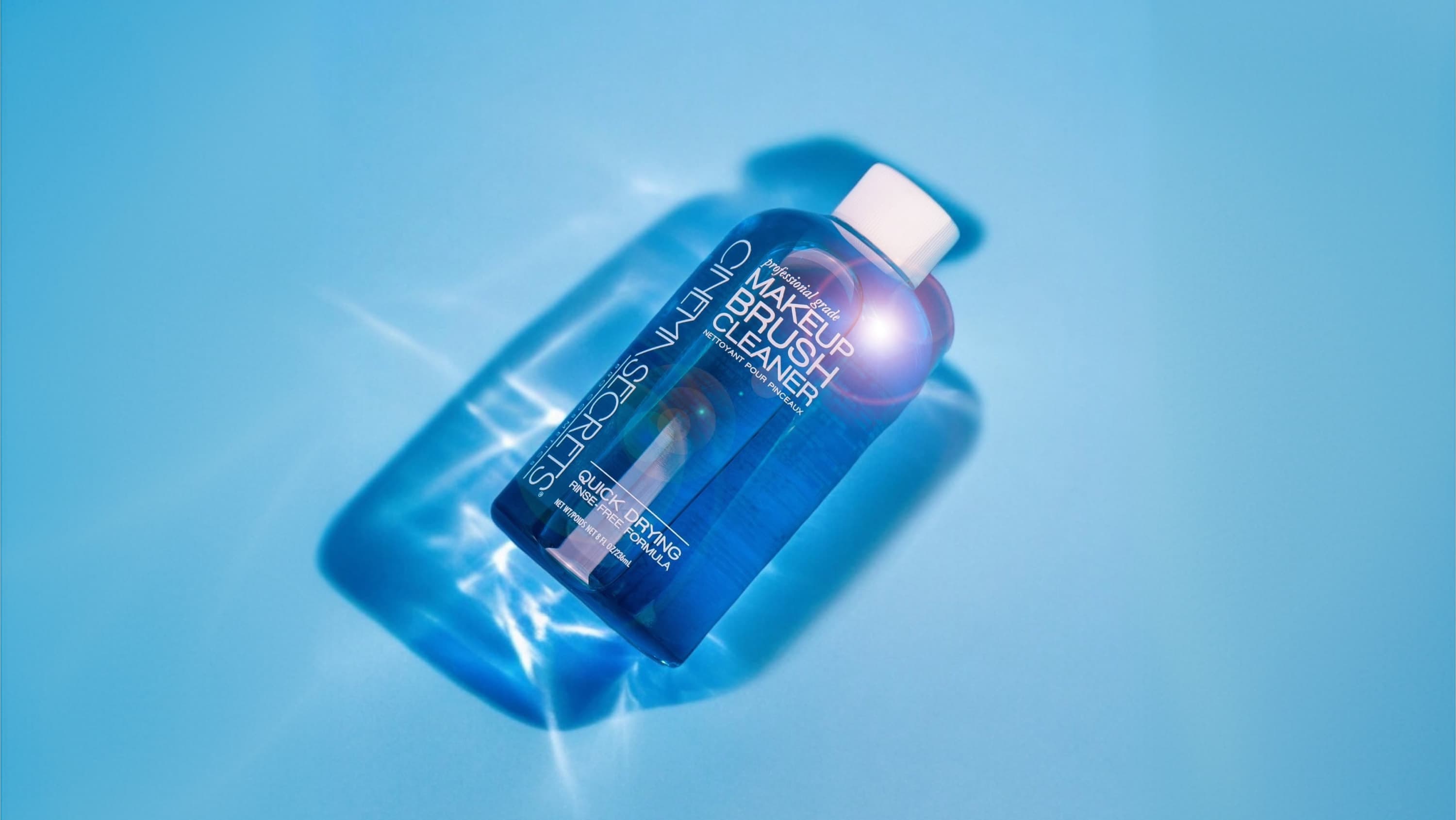 A blue bottle of Makeup Brush cleaner by Cinema Secrets in front of a pale blue background